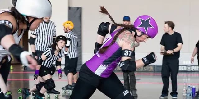 A jammer in purple skating with a star helmet cover